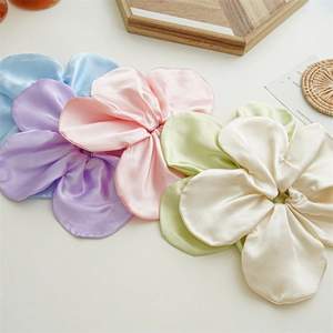 Detailed view of four satin floral scrunchies in blue, purple, pink and green tones