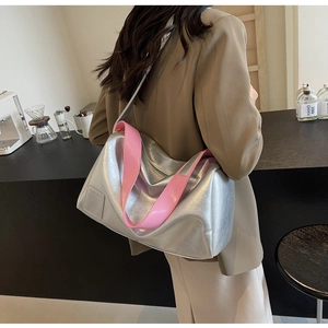 Detail of silver metallic Boston bag with pink shoulder strap worn by a model