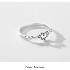 Macro shot of silver open ring with pavé heart design and side circular stones