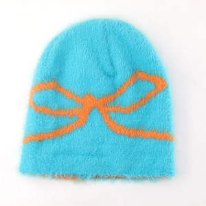 Close-up of bright blue knit beanie with soft plush texture and orange bow pattern