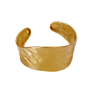 Minimalist irregular golden cuff bracelet with vintage hammered texture on white background