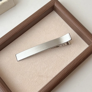 Gros plan d'une barrette en métal brossé argenté sur un plateau en velours beige élégant