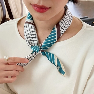 Detail showing a blue and white striped silk scarf tied in a small knot on a neck