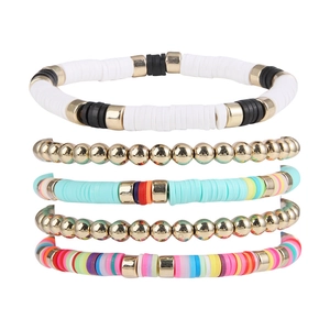 Gros plan d'un ensemble de 5 bracelets bohémiens en pâte polymère et perles d'or