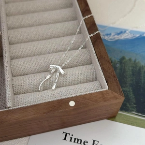Minimalist S925 sterling silver bow necklace displayed on a luxury velvet jewelry box
