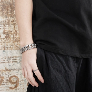 Close-up of a chunky silver stainless steel Cuban chain bracelet on a man's wrist
