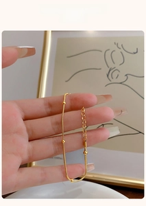 Detailed view of a gold snake chain bracelet with four beads on a woman's wrist