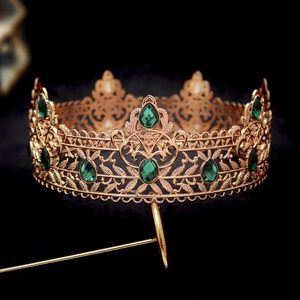 Close-up of golden baroque crown with emerald green gems and intricate metalwork