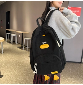 Detail of black corduroy backpack with cute yellow duck features and fashion label