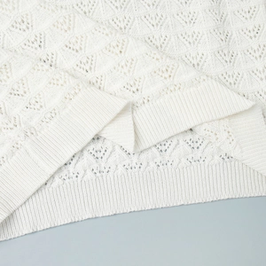 Detail of white hollowed knit texture and ribbed hem on a stylish short sleeve top