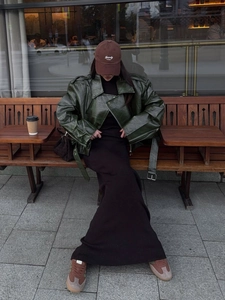 Close-up of a glossy dark green leather jacket and black ribbed knit skirt ensemble