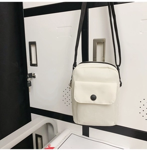 Detail of white nylon crossbody bag with black adjustable strap and round snap button