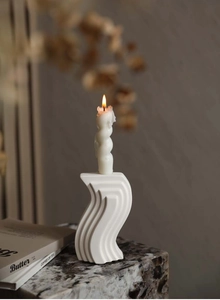 Detail of white S-shaped ceramic candle holder with spiral candle in a modern setting