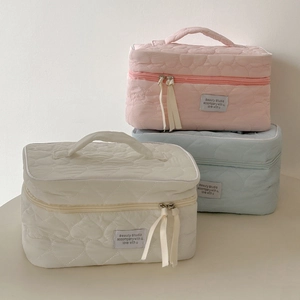 Close-up of quilted heart patterns on portable cosmetic bags in pink, beige, and blue