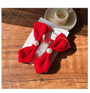 Close-up of red velvet bow hair clips with pearls on a professional display card