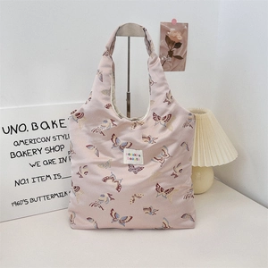 Detail of pink canvas tote bag featuring vibrant butterfly patterns and a woven logo label