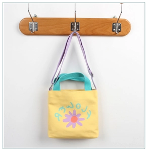 Detail view of yellow canvas bag with flower print and contrasting purple shoulder strap