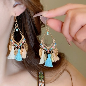 Detail of bohemian leaf tassel earrings featuring gold geometric frames and colored beads