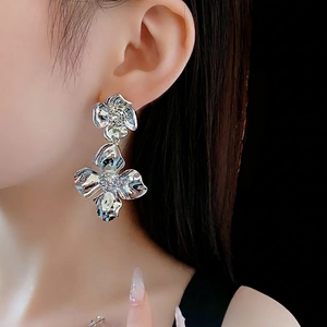 Silver flower drop earrings with liquid metal texture and crystal accents on model