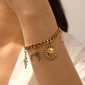 Detailed view of a gold chain bracelet featuring sun, moon, and star charms with beads