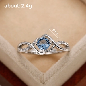 Wavy silver ring with 5mm round blue zircon and twisted pave band in a velvet box