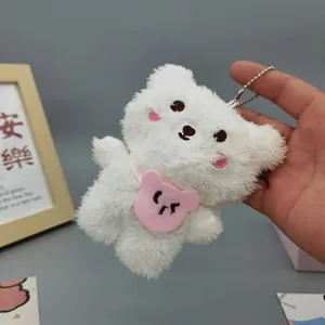 Close-up of white plush bear pendant with embroidered face and pink heart bag accessory