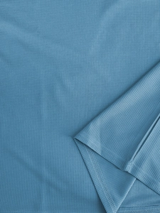 Detail shot of blue waffle knit fabric texture and double-stitch sewing on polo shirt