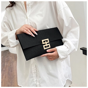 Detail of black crocodile texture handbag featuring a geometric gold metal clasp closure
