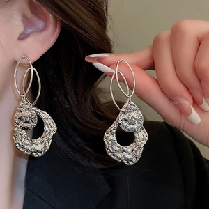 Gros plan de boucles d'oreilles géométriques argentées avec une finition métallique texturée