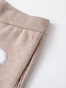 Detailed close-up showing the fine knit texture and ribbed cuff in oatmeal beige fabric