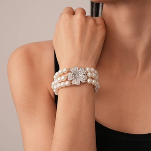 Detail of three-row pearl bracelet with a sparkling clover diamond clasp on wrist