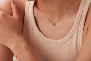 Close-up of a model wearing a gold 18K necklace and bracelet set with round zircon