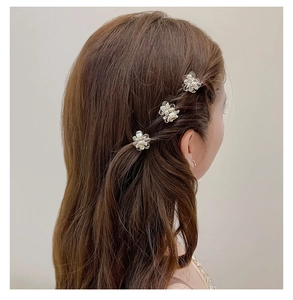 Detailed view of three mini camellia flower hair clips worn on styled hair