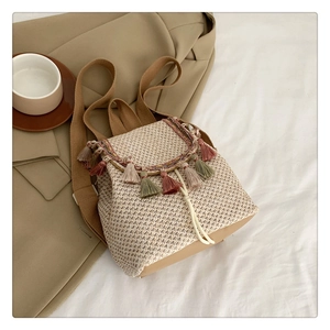 Detail of straw backpack showing multi-color tassels and woven texture with drawstring