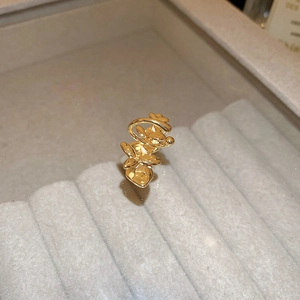 Detailed view of a gold-plated orchid ear cuff placed on a gray velvet jewelry box