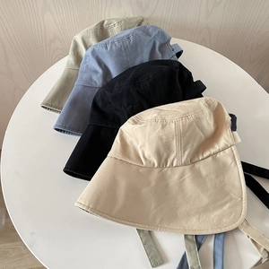Close-up of four wide brim bucket hats with long straps in beige, black, blue and green