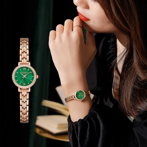 Detail of luxury rose gold watch with green dial, rhinestone bezel, and Roman numerals