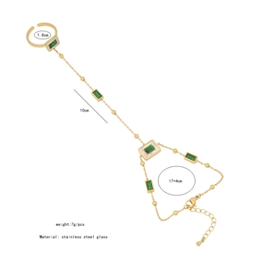 Detailed view of gold stainless steel finger bracelet with emerald green glass heart