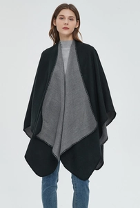 Detail of solid color knit poncho with contrasting stitched edges and black-gray split design