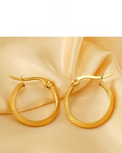 Macro view of 18K gold plated striped hoop earrings on elegant champagne silk fabric