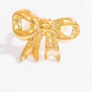 Detail of a minimalist golden bow-shaped ring with a polished glossy finish
