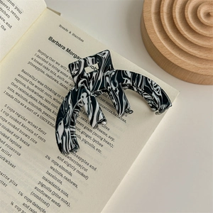 Detail of a black and white marble pattern acetate hair claw clip on an open book