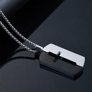Gros plan d'un pendentif croix en acier inoxydable noir et argent ajouré poli