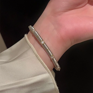 Detail of silver brushed metal bangle with gold accents and sparkling zircon stones