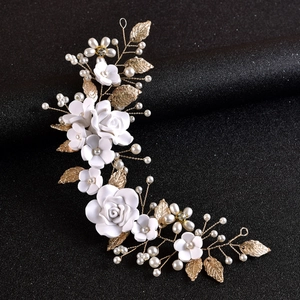 Detail view of handmade bridal headpiece with white clay flowers and golden leaves