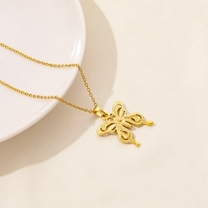 Detailed view of a golden butterfly pendant necklace on a ceramic plate background