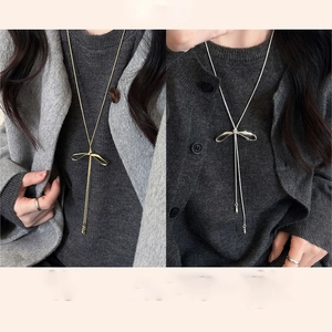 Detail of adjustable bow necklace with long tassels in gold and silver finishes