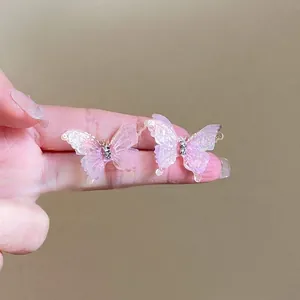 Détail de boucles d'oreilles papillon roses avec finition pailletée et strass brillants