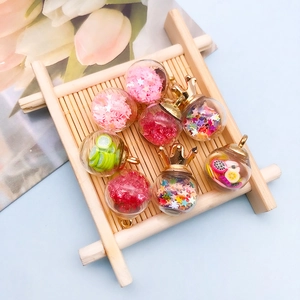 Macro shot of glass ball pendants with colorful stars and fruit slices for DIY jewelry