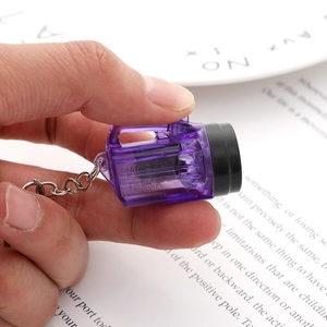 Mini purple transparent plastic flashlight keychain held in hand to show compact size